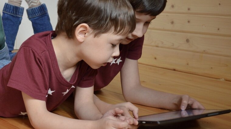 Zwei Kinder schauen auf ein Tablet.